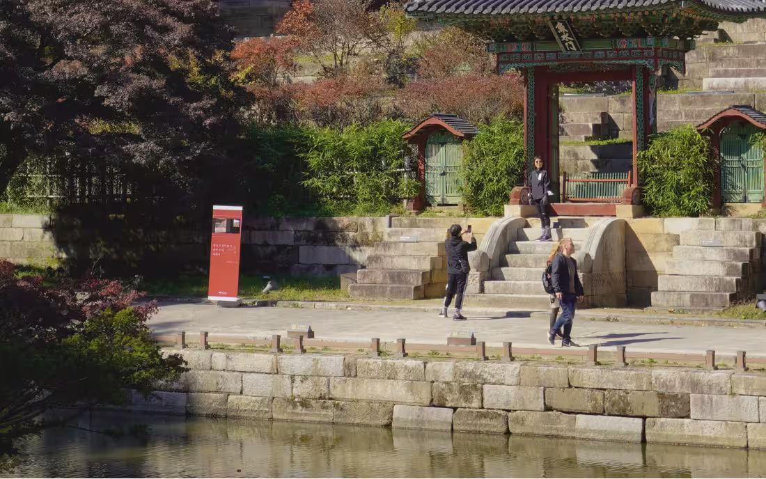 Turistas caminando por los senderos del Palacio Changdeokgung en otoño